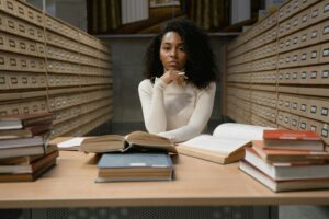 a woman with curly hair sitting on a table with stacks of books